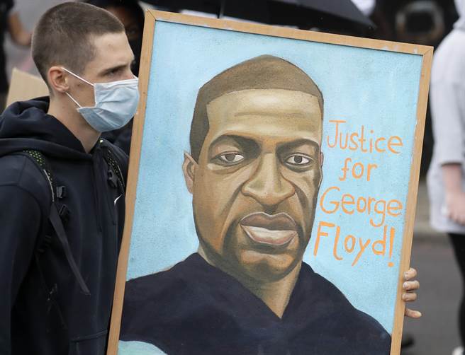 非裔男子佛洛伊德的官方验尸报告出炉，显示他死于心肺停止，而非窒息，图为抗议者拿着他的肖像，要求司法正义。（美联社）