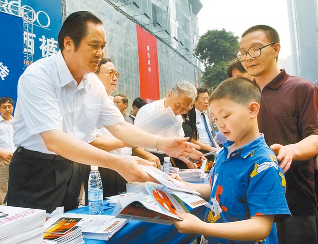 2004年6月26，時任重慶市公安局長朱明國（左一），在街頭向青少年及家長發放禁毒宣傳資料。（新華社資料照片）