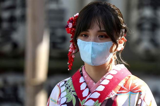 新冠肺炎疫情在日本境內持續延燒，日本街頭穿著和服戴口罩的女性。(路透社)