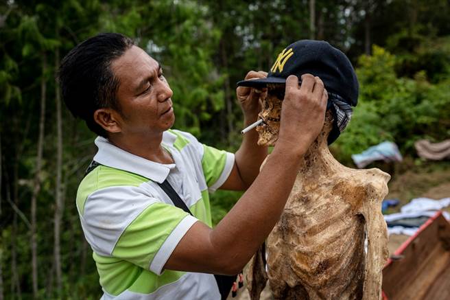 印尼托拉雅族人每年扫墓会重新将祖先遗体从坟墓中挖出，为祖先打理一番，甚至让对方吸口菸。（图／TPG、达志影像）