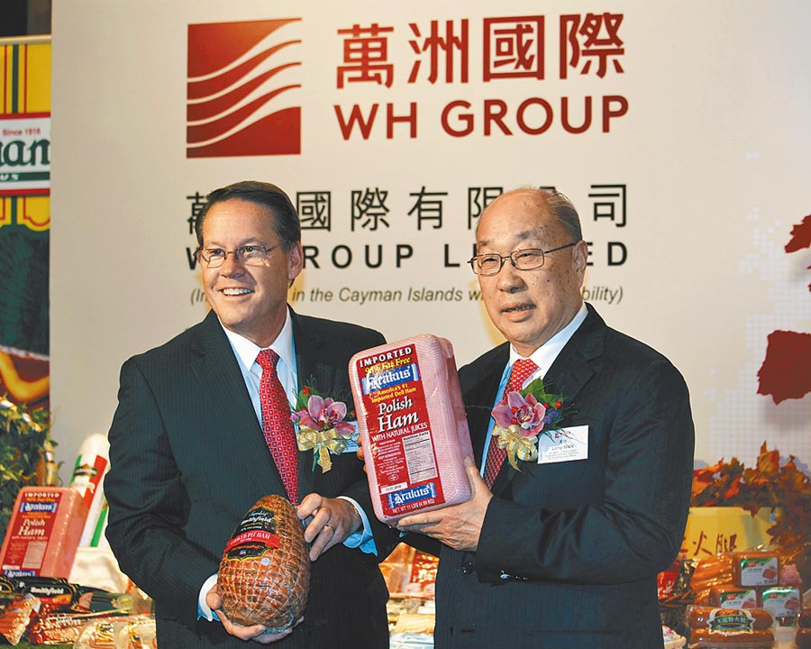 陸企萬洲國際董事長萬隆（右）與美國史密斯菲爾德執行長larry pope，2014年在香港召開記者會前，大秀旗下肉類產品。（路透）