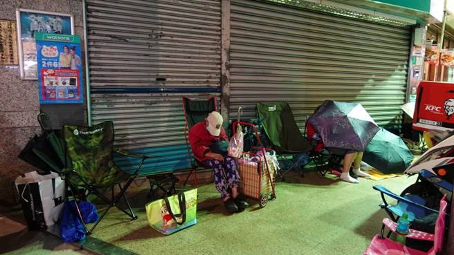 民眾打地鋪、撐傘擋風排隊。（照片/游定剛 拍攝）