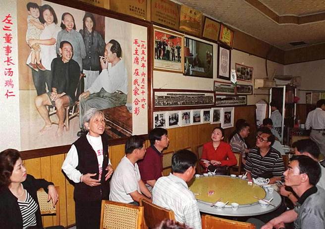 1999年，曾与毛泽东合影的汤瑞仁（站立者）在毛泽东故居对面开起了「毛家饭店」﹐每天顾客盈门。这是她在向顾客介绍毛泽东当年回韶山的情景。（新华社）
