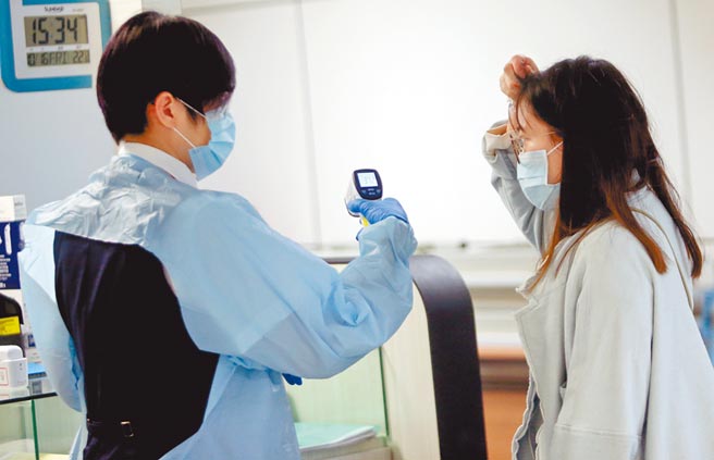 国内昨新增4例境外移入个案，在桃园机场入境管制区的发烧筛检站中，检疫人员正为1名入境旅客量测体温。（范扬光摄）