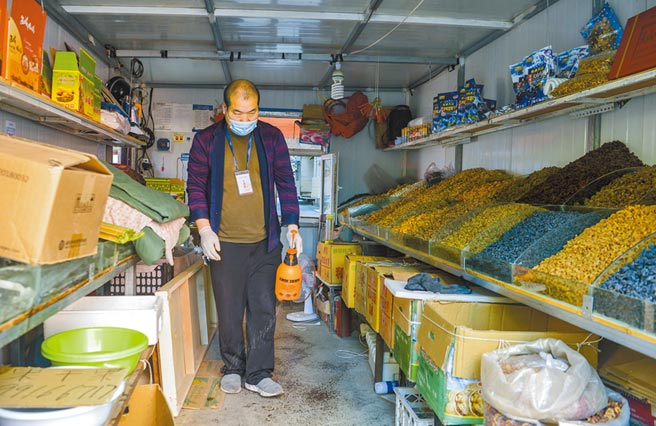 新疆乌鲁木齐，一家水果商户在店舖内喷洒消毒液并准备开门营业。（中新社资料照片）