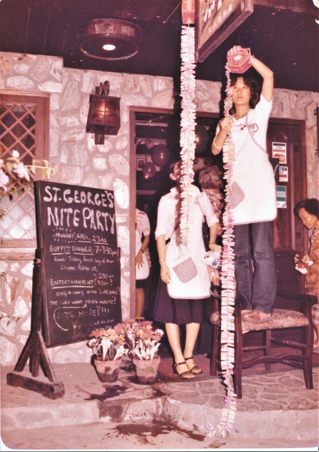 妹妹在餐馆举办的St. George’s Nite Party，布置会场。只见她穿着员工制服，在餐馆门口，身先士卒，爬上椅子，挂起一串又一串的鞭炮，准备迎接客人到来。（罗青提供）