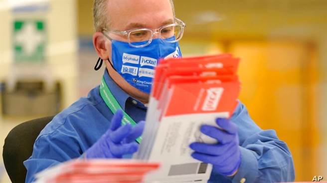 一名选务人员对选票进行分类。(图/美联社)