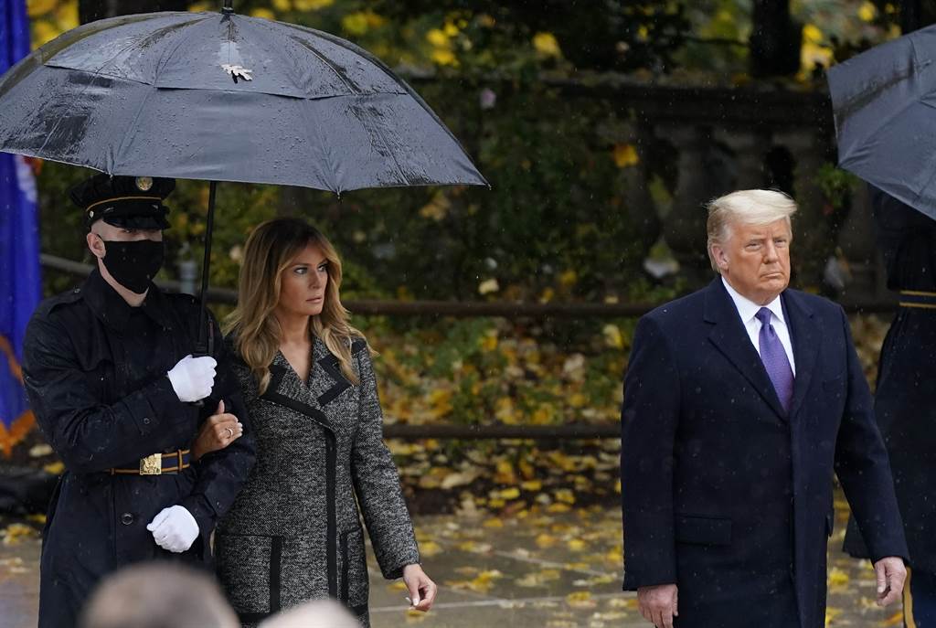 第一夫人梅蘭妮亞11月11日退伍軍人節當天，隨著美國總統川普在雨中造訪阿靈頓國家公墓（Arlington National Cemetery）時，右手緊扣著撐傘軍人的臂膀，望著另一半。（美聯社）