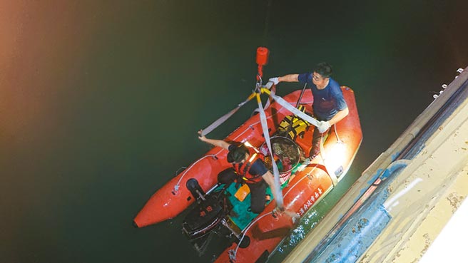 消防员搭配动保人员以橡皮汽艇打捞起溺毙的小黄狗。（程炳璋摄）