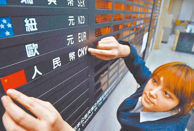 美国货币无限宽松，让人民币成为避险资产。图为银行行员指着人民币匯率。（本报资料照片）