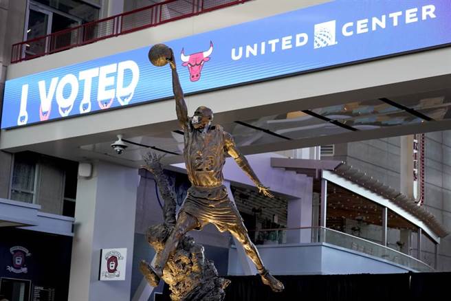 公牛队主场联合中心外的乔丹雕像被戴上口罩，后方还在今年美国大选期间挂上催票看板。（美联社资料照）