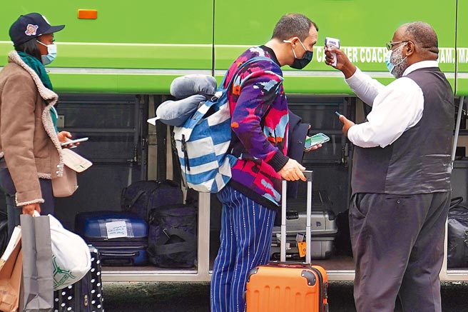 纽约市曼哈顿区，一名巴士司机正在为上车的旅游量体温。感恩节期间，美国有数以百万计民眾搭乘公共交通工具返家过节。（路透）