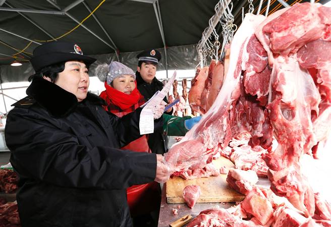 山東青島食品藥品監督管理局工作人員在一家農貿市場對肉類食品進行抽查。（新華社資料照片）