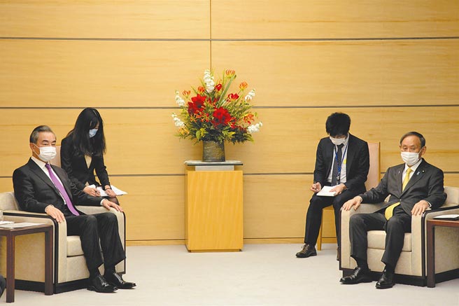 11月25日，日本首相菅义伟（前右）在东京会见访日的大陆外交部长王毅。（中新社）