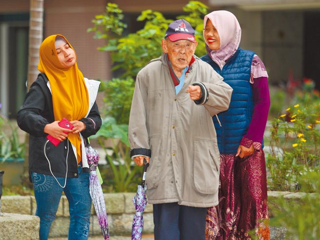 印尼移工境外移入病例暴增，政府決定暫緩來台2周，國內充滿「等不到」的家庭。圖為印尼看護工陪著雇主到庭院散步。（陳怡誠攝）