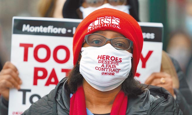 美国29日染疫住院人数已超过9万3000人，再创新高。图为一名正在罢工的护士。（美联社）