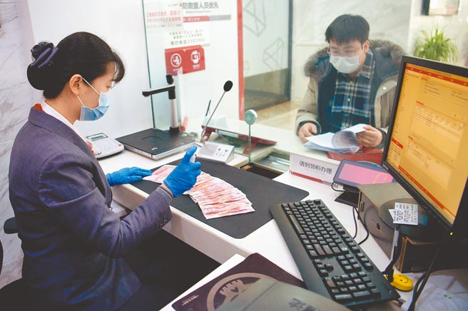 疫后大陆富豪偏爱现金等低风险资产。图为银行职员在为民眾办理存款业务。（中新社）
