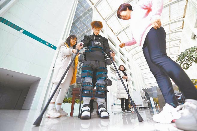 經過數月康復訓練的博文，穿上外骨骼康復訓練機器人，手拄拐杖站立起來，這讓他看到了康復的曙光。（和冠欣攝）