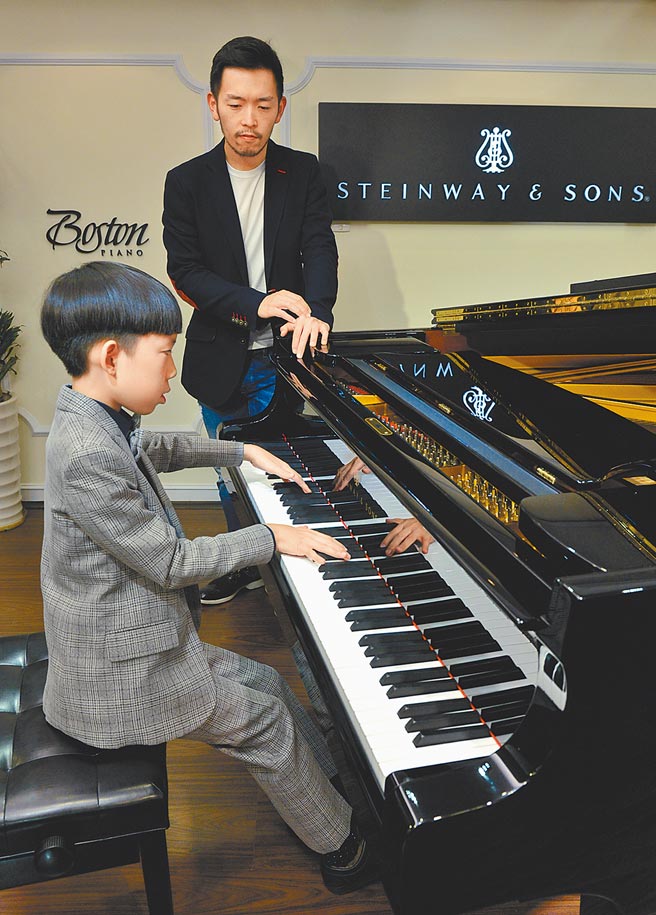 钢琴家严俊杰（后）与学生林灏维（前）。（本报资料照片）