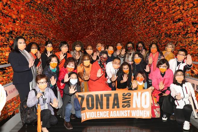 眾人在新北歡樂耶誕城的橘色香榭光廊合體快閃，現場亮起一片溫暖橘光，象徵各國攜手對抗性別暴力。（許哲瑗攝）