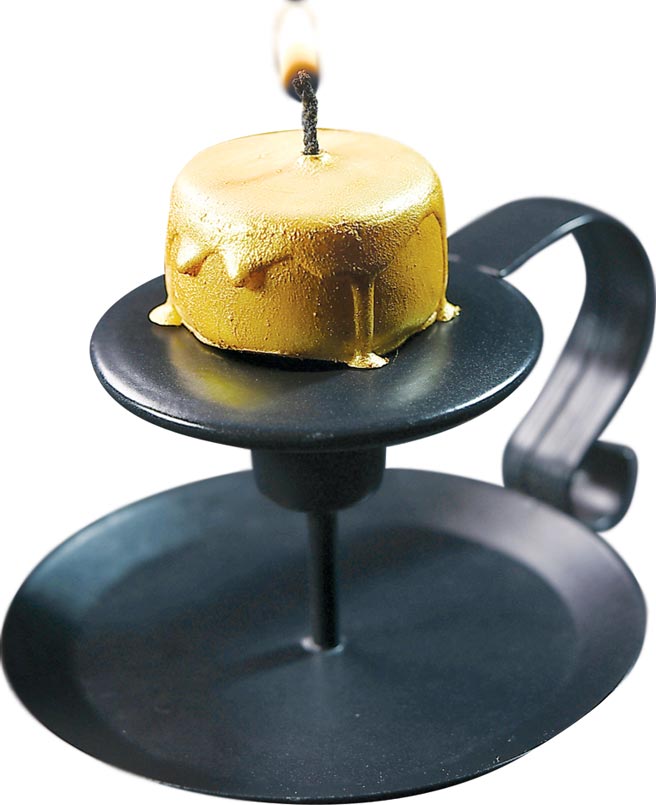 這道甜點形色像蠟燭，其實它是一個以檸檬卡士達為內餡的白巧克力，最外層塗敷了細緻的食用金粉。圖／姚舜