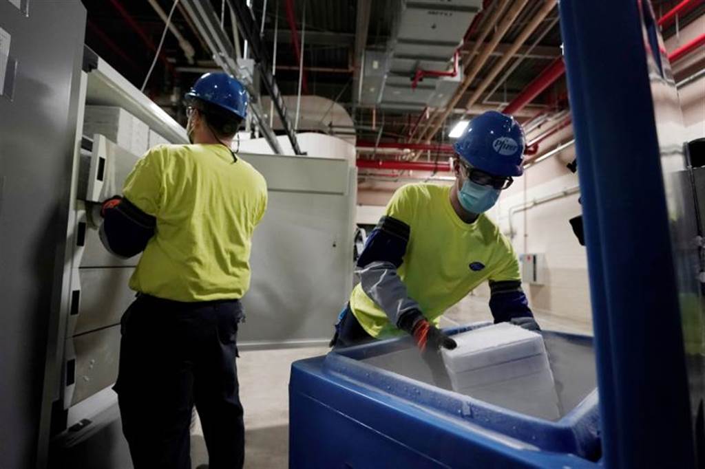 工作人员将疫苗自冰箱取出，随后放入蓝色冰藏箱中，以确保运送过程处于低温。图/路透社(photo:ChinaTimes)