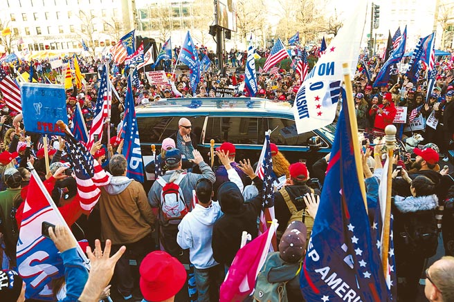 美国总统川普的支持者12日在华府参加游行时，包围了一辆汽车，他们误以为川普坐在车内。（路透）