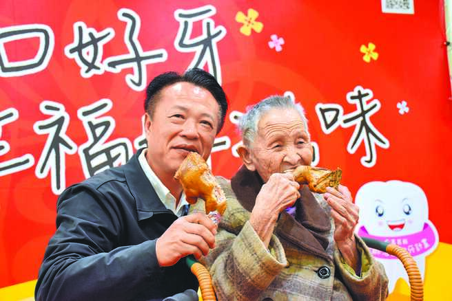 嘉义县长翁章梁（左）上任后推动乐龄活动假牙补助，14日人瑞陈阿嬷（右）大口啃鸡腿，展现装假牙成果。（吕妍庭摄）