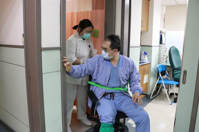 王医师将自己固定在椅子上，由护理人员协助移动诊察。（嘉基医院提供）