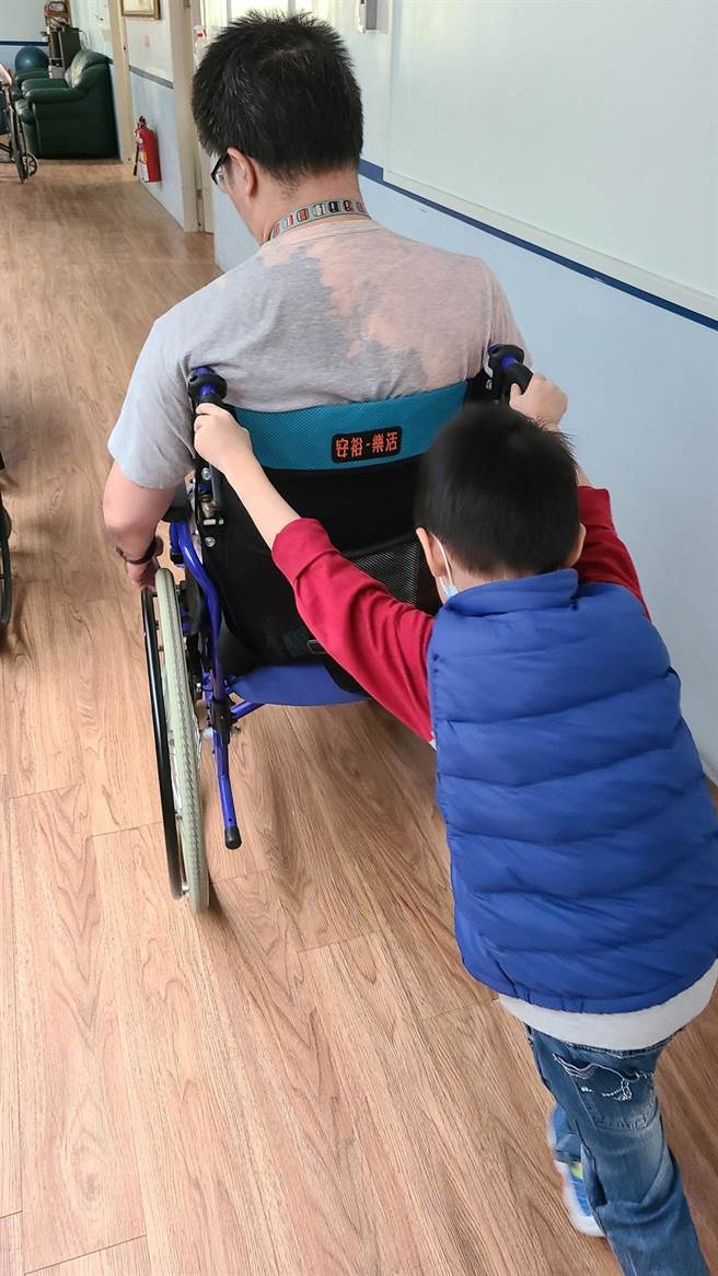 凤翔分队消防员赖统生的妻子PO出照片，儿子以小小身躯推着坐着轮椅的爸爸，画面惹人鼻酸。（翻摄脸书社团「我们消防家族」）