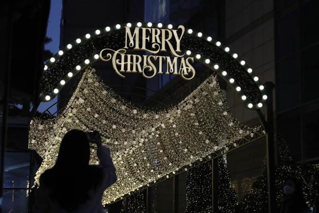 一名南韩女子20日在首尔一处圣诞节灯饰下拍照。（美联社）