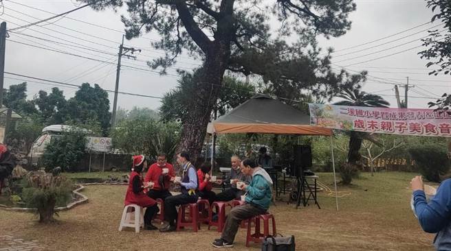 台南市大内区二溪国小23日举办「一家一菜亲职共餐音乐飨宴」，师生在校园老树下惬意用餐。（台南市二溪国小提供／刘秀芬台南传真）