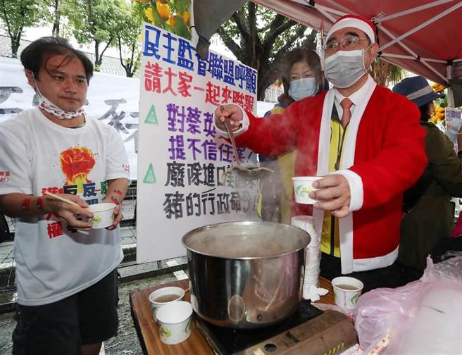 穿着圣诞老公公衣帽的新党主席吴成典（右）24日带领新党议员潘怀宗等人在立法院大门口，告诉民眾，最后一碗猪肝汤的意义。吴成典舀起最后一碗没有莱剂的猪肝汤，分送给在现场反莱猪进口的声援民眾。（刘宗龙摄）
