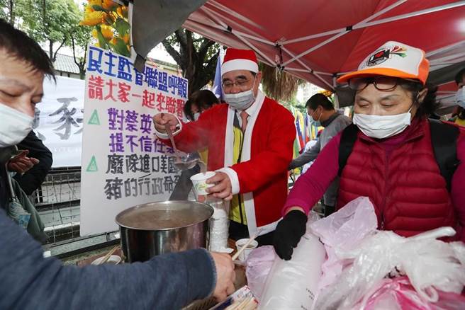 穿着圣诞老公公衣帽的新党主席吴成典（中）24日带领新党议员潘怀宗等人在立法院大门口，告诉民眾，最后一碗猪肝汤的意义。吴成典舀起最后一碗没有莱剂的猪肝汤，分送给在现场反莱猪进口的声援民眾。（刘宗龙摄）
