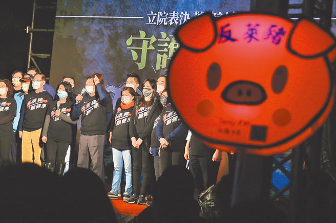 国民党23日举办「守护食安之夜」，有民眾带着反莱猪的发光看板，与台上立委相辉映。（图／本报系资料照）