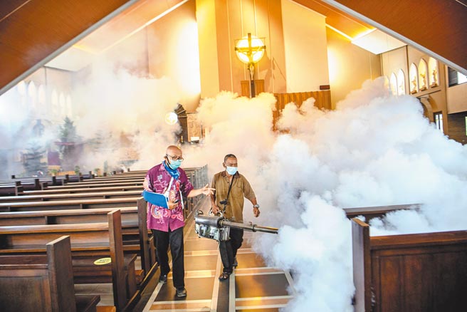 印尼新冠疫情大流行，教会人员在耶诞节弥撒之前为教堂消毒。（路透）