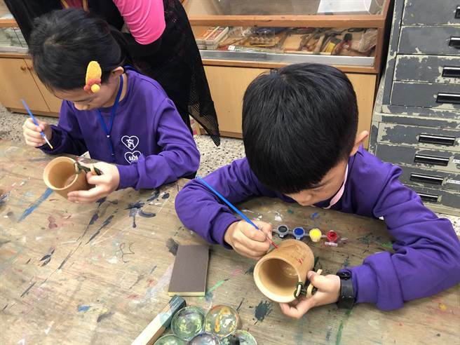 小朋友专注神彩绘环保竹杯。（魏怡嘉摄）