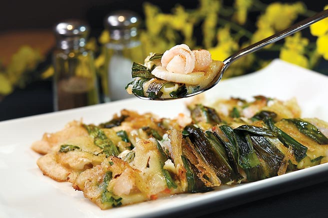 〈海鲜煎饼〉用了鱿鱼、鲜虾与干贝等海鲜食材，搭配洋葱、韭菜和红萝卜煎制，用料颇丰。图／姚舜