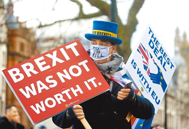 一名反脱欧人士24日在伦敦唐寧街举着标语牌示威，其中一面写着「脱欧不值得」，另一面则为「最佳协议就是留欧」。（路透）