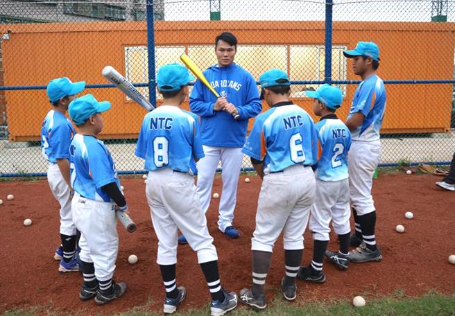 范国宸（中）细心指导八里国小的小球员打击练习。（富邦悍将提供／廖德修台北传真）