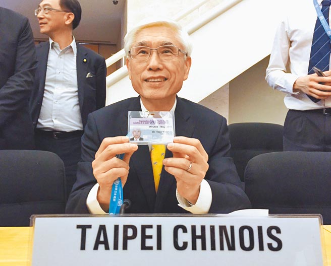 蔡英文总统上任后，卫福部长林奏延在世卫大会会场试坐中华台北座位，并开心出示「中华台北」与会证件。（中央社）