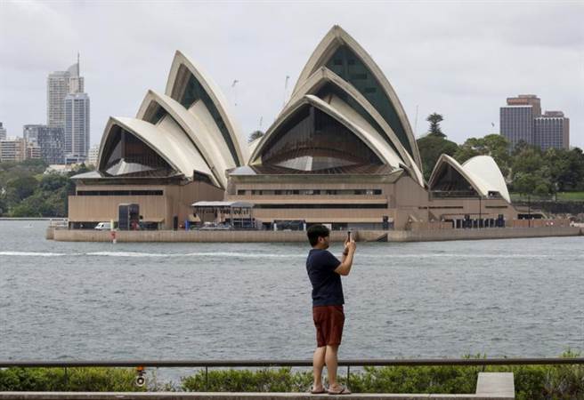 由於疫情影響，雪梨歌劇院周遭道路封鎖，然已有民眾在空曠地帶預作準備，準備欣賞跨年煙火秀。(圖/美聯社)