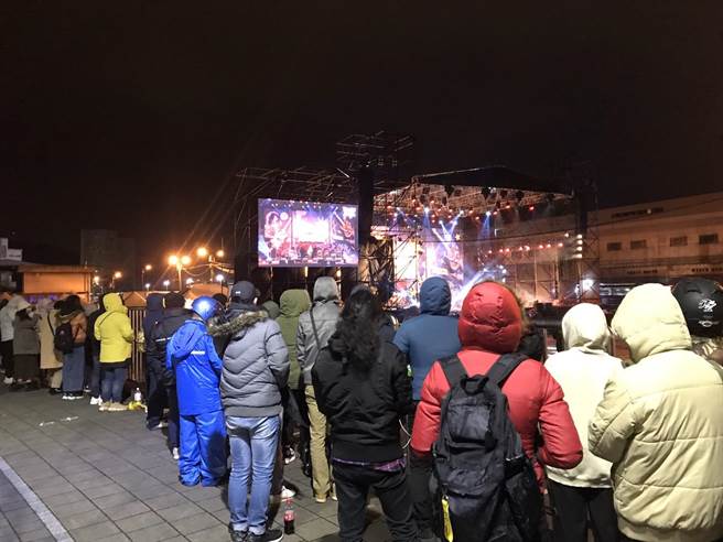 約60名民眾在人行道上看表演，盡管飄起小雨，仍澆不熄熱情。（陳彩玲攝）