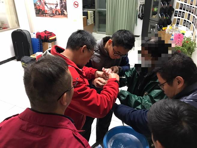 消防队员以棉花棒沾去光水，小心翼翼的去除手指与瓶身间的乾合胶水。（烈屿消防分队提供）