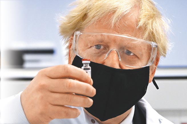 英国政府30日批准牛津大学/阿斯特捷利康药厂研发的新冠疫苗，并订于明年1月4日开始施打。图为英国首相强生拿着1剂牛津疫苗。（美联社）
