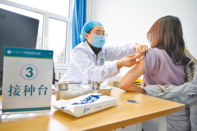 12月28日，呼和浩特市，工作人员给一位女子接种新冠病毒疫苗。（中新社）