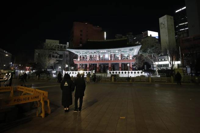 韩国近期疫情升温，首尔跨年例行敲钟仪式也取消，但仍有少数民眾到钟阁现场感受跨年气氛。（美联社）