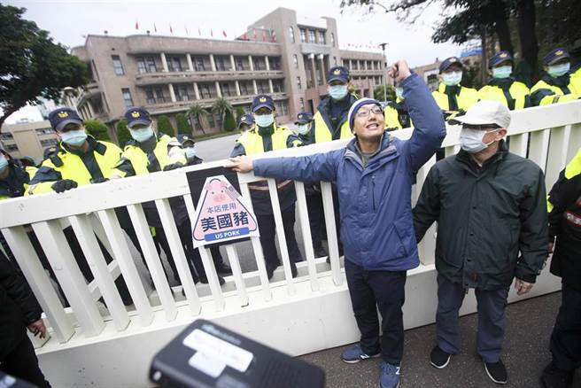 民间反瘦肉精毒猪联盟1日举办元旦升旗活动，数名成员朝凯道前进抗议，最后群眾抵达行政院，派代表将反莱猪标志贴在行政院大门上，并预告后续还会有反莱猪的具体行动。（张铠乙摄）
