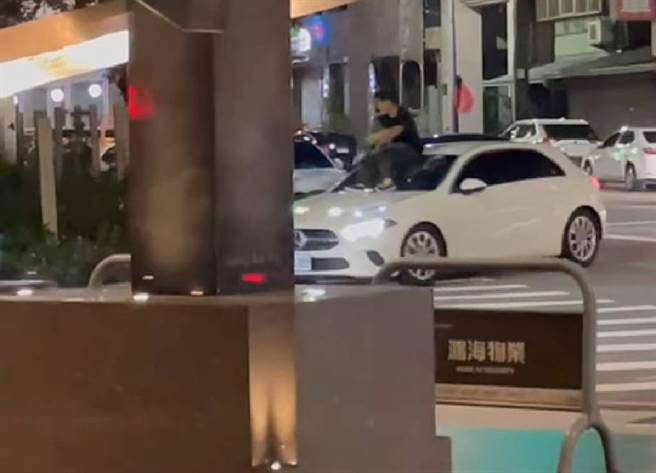 有网友在脸书社团《爆料二社》贴出相当夸张的照片，一名男子当街跳上一辆白色宾士车引擎盖，还拿着类似铁鎚的工具狂敲挡风玻璃。警方调查后发现，原来是夫妻吵架，丈夫爆怒后怒砸妻子轿车。（照片来源：脸书社团《爆料二社》）