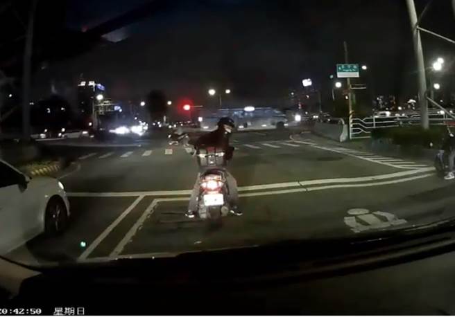 等紅燈騎士回頭看到有車輛遭警方追逐急閃避。 